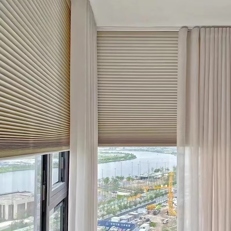 Beige honeycomb cellular shades and ripple fold curtains installed in modern high-rise apartment with city view