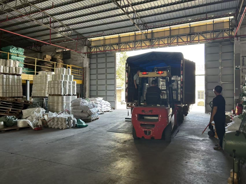 Factory manager operating red forklift to unload curtain tape shipment in warehouse facility