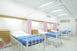 Multi-bed hospital ward with pink privacy curtains on ceiling-mounted curtain track runners